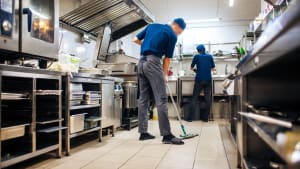 Deux personnes nettoient la cuisine d'un restaurant