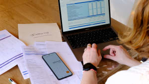 Personne faisant ses impôts avec ordinateur, papiers et calculatrice. impot