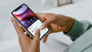 Personne utilisant une application bancaire sur un smartphone blanc.