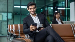 Un homme d'affaires caucasien utilise un t�l�phone mobile intelligent en attendant dans le salon d'affaires de la compagnie a�rienne en attendant l'embarquement pour l'utilisation de l'avion.
