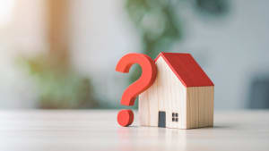 Maison en bois avec un point d?interrogation rouge.