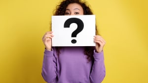 Femme afro-américaine avec un signe de point d'interrogation sur fond jaune