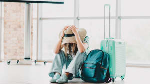Jeune femme assise dans un terminal d'a�roport avec des bagages assise la t�te entre les mains.