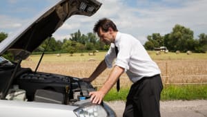 Un homme devant sa voiture en panne.