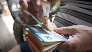 Une personne compte des billets de banque en euros.
