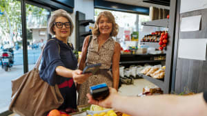 Deux femmes paient des courses avec un téléphone dans magasin.