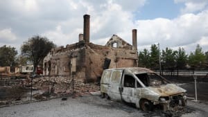 Maison et voiture br�l�es apr�s un incendie, ruines visibles.