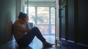 Une femme assise sur le sol dans le couloir de son appartement.