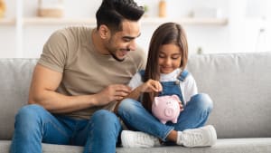 Petite fille et papa économisant de l'argent dans une tirelire