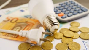 Une calculatrice, une ampoule et des pièces pour symboliser le coût de l'électricité.
