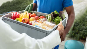 Livraison d'une caisse de légumes et de fruits.