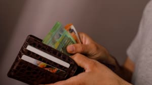 Gros plan des mains d'une personne tenant un portefeuille en cuir marron rempli de billets en euros et de cartes de cr�dit