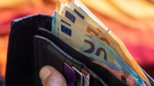 Portefeuille noir rempli de billets en euros et de cartes de crédit tenu à la main