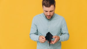 Je suis fauch�. Portrait d'un homme barbu triste et en faillite montrant son portefeuille vide regardant la cam�ra. Homme contrari� se tenant isol� sur un fond de studio jaune. Concept de pauvret�. Manque d'argent