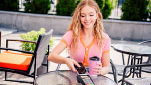 Portrait d'une charmante fille positive buvant du caf� le matin, le week-end, paiement sans esp�ces au caf� restaurant � l'ext�rieur