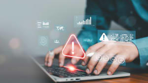Mains tapant sur un ordinateur portable avec une alerte d'avertissement lumineuse et une interface de tableau de bord de données virtuelles. Concept de risque de cybersécurité, détection d'erreurs système, protection des données, technologie de surveillance de la sécurité en ligne