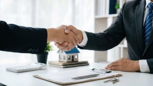 Deux hommes se serrent la main après une transaction immobilière.