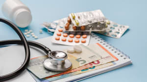 Des billets de banque et un stéthoscope et des médicaments.