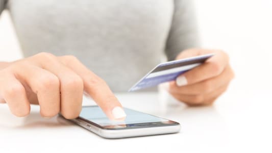 Gros plan de femme utilisant un smartphone et une carte bancaire