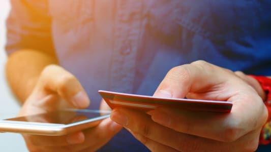 Gros plan d'un homme utilisant un mobile et une carte bancaire