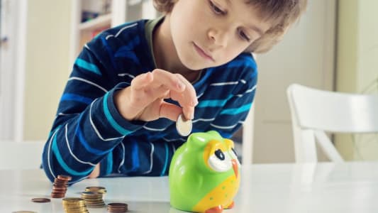 Enfant mettant des pices dans une tirelire 