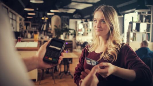 Jeune femme rglant un achat par carte bancaire