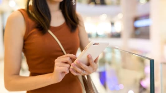 Femme utilisant un smartphone dans une galerie marchande