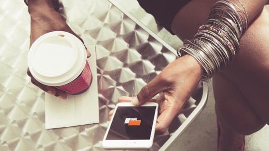 Un femme utilise l'application Orange Bank dans un caf