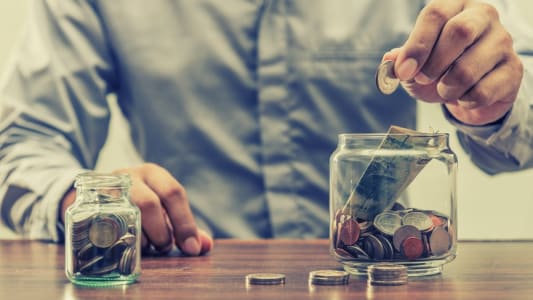 Homme qui met de l'argent dans un bocal