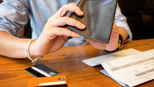 Homme fouillant un portefeuille vide