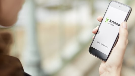 Une femme consulte l'application Fortuneo sur son smartphone