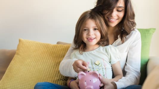 Mre et fille mettant de l'argent dans une tirelire