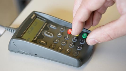 Personne entrant son code de carte bancaire sur un terminal de paiement lectronique
