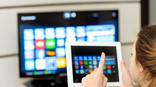 Une femme consultant sa tablette devant la tlvision