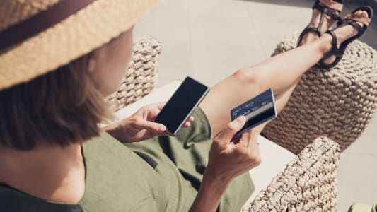 Jeune femme en vacances utilisant sa carte bancaire et son mobile