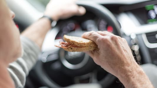 Un conducteur mange un sandwich au volant