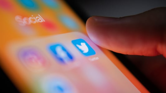 Un usager d'iphone touche le logo Twitter sur son cran