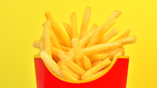 Cornet de frites rouge sur fond jaune