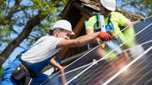 hommes installant des panneaux solaires sur un toit