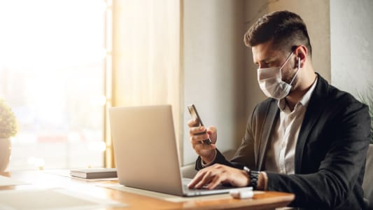 banquier devant son ordinateur portant un masque