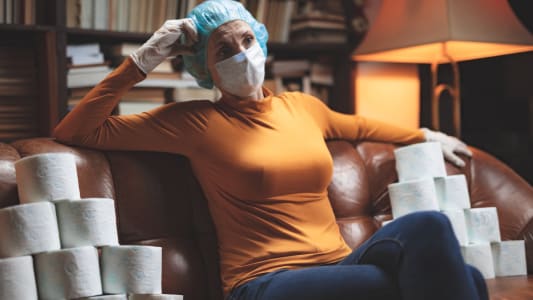 Femme masque et rouleaux de papier toilette