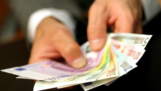 un homme tenant des billets en euros