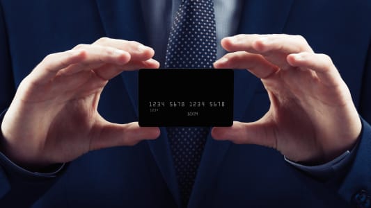 Un homme en costume prsente une carte bancaire noire