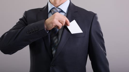 Un homme en costume range sa carte bancaire dans sa poche