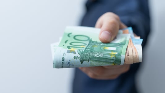 Un homme tient une liasse de billets en euros