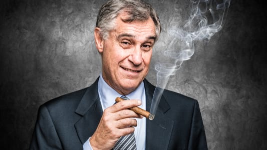 Un homme d'affaire souriant fume un cigare