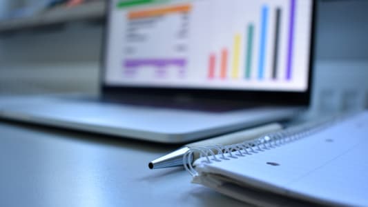 un cahier devant un ordinateur portable