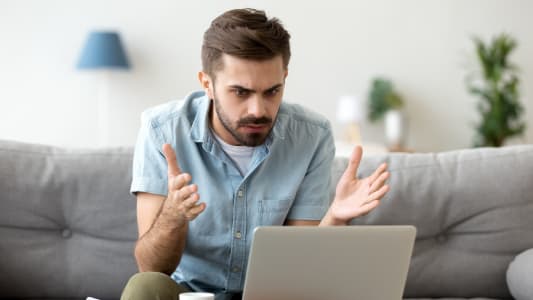 Un homme en colre devant son ordinateur portable