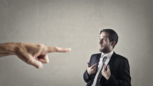 Un homme en costume pointé du doigt