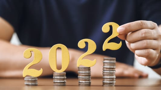 Homme posant les chiffres 2022 sur des piles de pices de monnaie